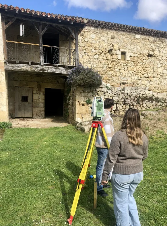 Installation de la station totale topographique devant la grange